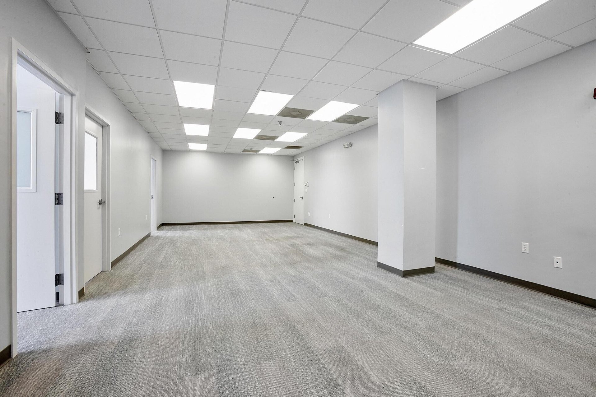 Bright open office space with neutral carpeting and overhead lighting