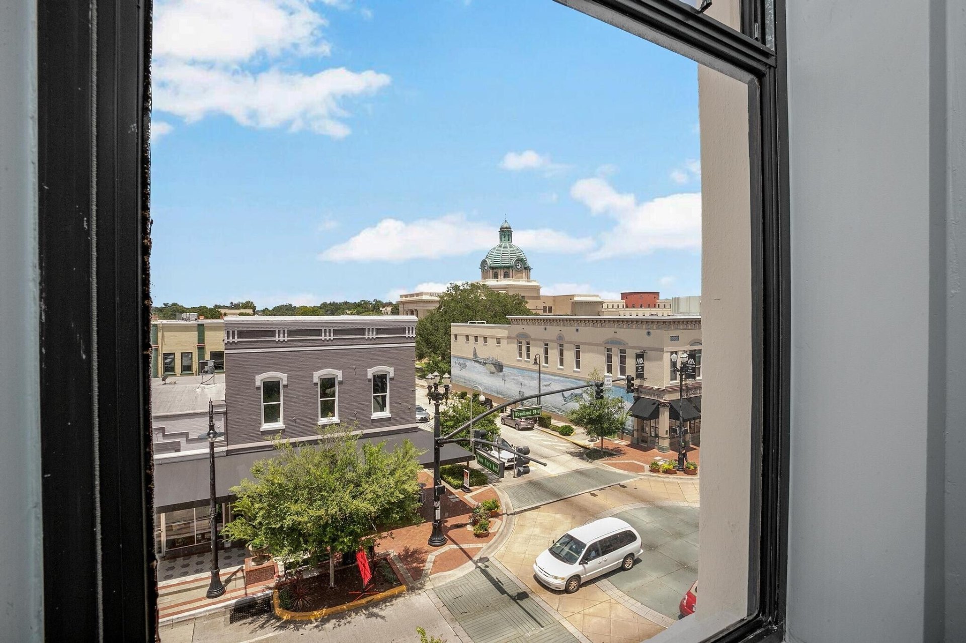 Window view of downtown DeLand rooftops, brick streets, and the historic courthouse